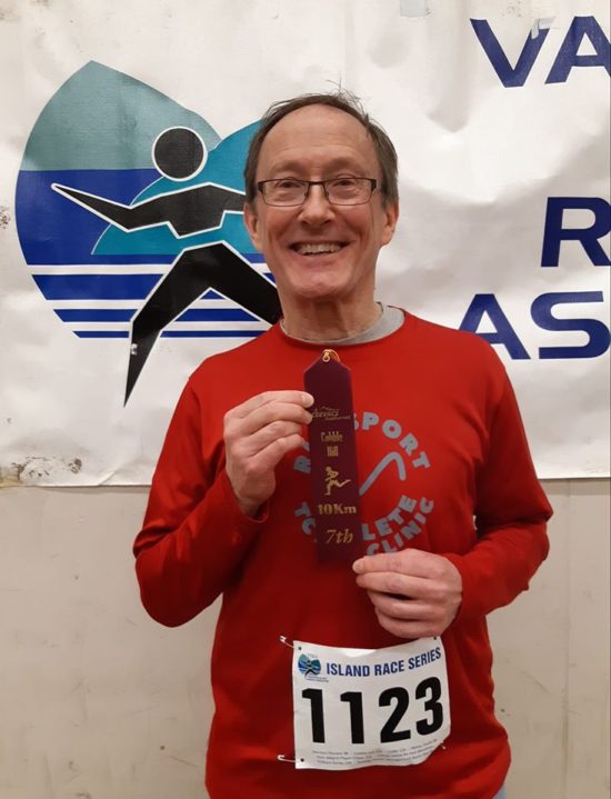My run coaching client Howard posing with his Age Group Award and smiling about his personal best 